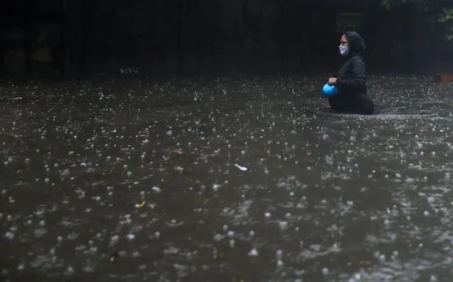 A woman wearing a mask walks through a waterlogged street in Mumbai, India, Monday, May 17, 2021. Cyclone Tauktae, roaring in the Arabian Sea was moving toward India's western coast on Monday as authorities tried to evacuate hundreds of thousands of people and suspended COVID-19 vaccinations in one state. (Photo by Rafiq Maqbool/AP Photo)