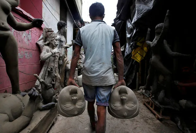 An artisan carries clay-face sculptures of the Hindu goddess Kali in an alley ahead of the Kali Puja festival in Kolkata, India October 29, 2018. (Photo by Rupak De Chowdhuri/Reuters)