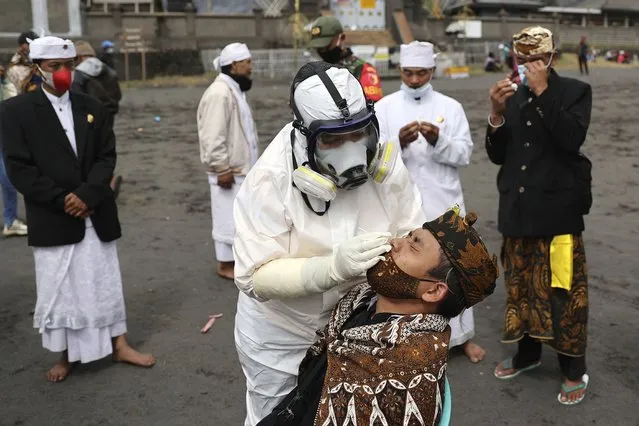 A Hindu devotee has his nasal swab sample collected by a medical worker to be checked for coronavirus before he takes part in the upcoming Yadnya Kasada festival, at Luhur Poten Temple at near Mount Bromo, Probolinggo, Indonesia, Friday, June 25, 2021. The Yadnya Kasada festival is where local Hindus gather to make offerings of rice, fruit, vegetables, livestock or money are made to gods at the active volcano to ask for blessings and assure a bountiful harvest. (Photo by Trisnadi/AP Photo)