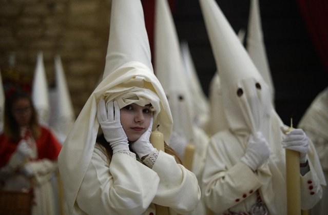 Hooded penitents from “La Borriquita” brotherhood take part during a Holy Week procession in Cordoba, Spain, Sunday, March 29, 2015. (Photo by Manu Fernandez/AP Photo)