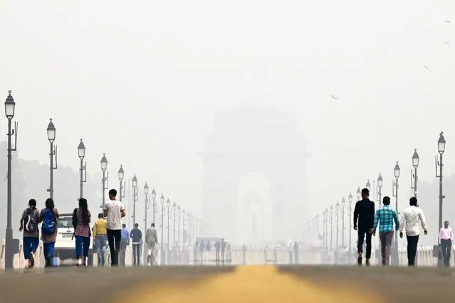 People walk along the Kartavya Path near India Gate amid heavy smog conditions in New Delhi on November 3, 2023. Schools were shut across India's capital on November 3 as a noxious grey smog engulfed the megacity and made life a misery for its 30 million inhabitants. (Photo by Arun Thakur/AFP Photo)