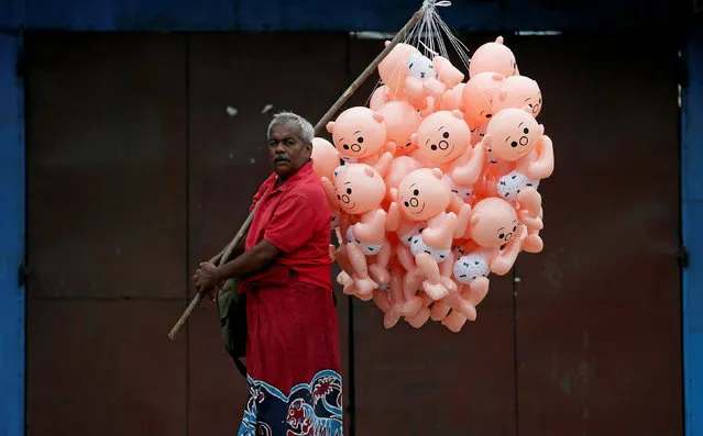 A vendor looks on as he walks along a main road to sell balloon baby toys in Colombo, Sri Lanka November 30, 2016. (Photo by Dinuka Liyanawatte/Reuters)