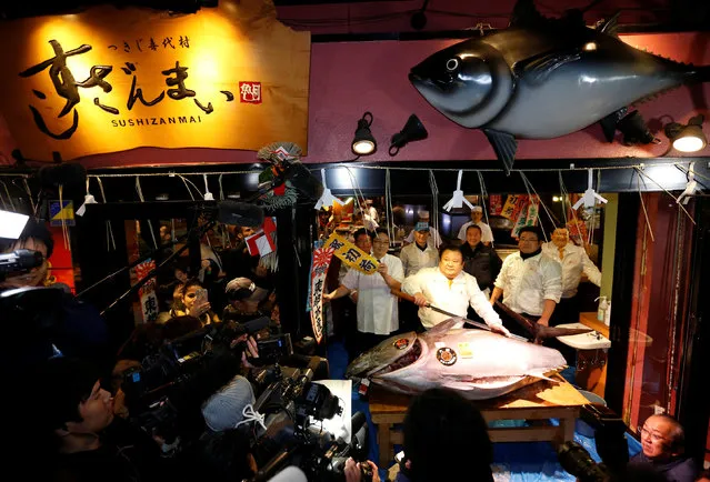 Kiyomura Co's President Kiyoshi Kimura (C), who runs a chain of sushi restaurants Sushi Zanmai, holds a sword as he poses with a 212 kg (467 lbs) bluefin tuna at his sushi restaurant outside Tsukiji fish market in Tokyo, Japan, January 5, 2017. (Photo by Issei Kato/Reuters)