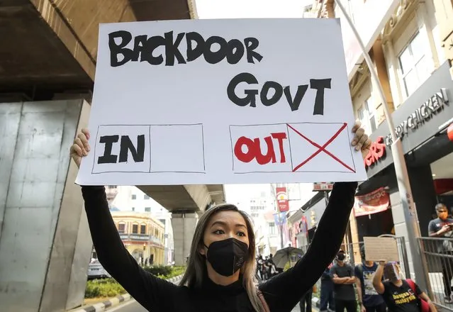 A protester holds a placard during a demonstration demanding the prime minister step down near the Independence Square in Kuala Lumpur, Saturday, July 31, 2021. Hundreds of black-clad Malaysian youths have rallied in the city center, demanding Prime Minister Muhyiddin Yassin resign for mismanaging the coronavirus pandemic that has worsened. (Photo by F.L. Wong/AP Photo)