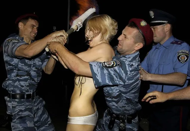 An activist from the Femen movement, which stages topless protests, is detained by police after exposing herself in Kiev, Ukraine, on June 17, 2013. (Photo by Sergei Chuzavkov/Associated Press)