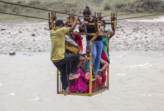 Group of Nepalese use rope bridge as they crossing the Trishuli river, near the Fhading Village in Dhading Disrict, some 90 kilometers from capital Kathmandu, Nepal. 14 April 2015. Farmers, students and villagers from the other side of the Trishuli river have to use different methods to cross the river after local authorities failed to build a promised bridge. (Photo by Narendra Shrestha/EPA)