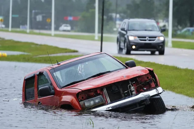 An abandoned vehicle is half submerged in a ditch next to a near flooded highway as the outer bands of Hurricane Ida arrive Sunday, August 29, 2021, in Bay Saint Louis, Miss. (Photo by Steve Helber/AP Photo)