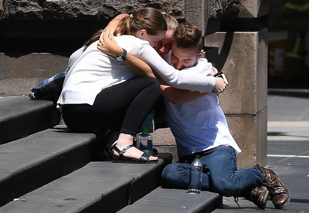Pedestrians hug on the steps of a building near the road where a car hit pedestrians in central Melbourne, Australia, January 20, 2017. (Photo by Julian Smith/Reuters/AAP)
