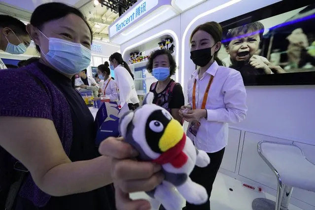 A woman holds up a soft toy at the Tencent booth during the China International Fair for Trade in Services (CIFTIS) in Beijing Monday, September 6, 2021. Beijing has launched anti-monopoly and data security crackdowns to tighten control over internet giants including e-commerce platform Alibaba Group and games and social media operator Tencent Holdings Ltd. that looked too big and potentially independent. (Photo by Ng Han Guan/AP Photo)