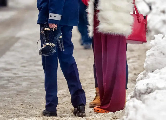 A policewoman holds a pair of high heel boots belonging to a clubber standing next to her who came to retrieve belongings, after firefighters put out a fire that erupted in the early hours at the upmarket Bamboo nightclub, in Bucharest, Romania, Saturday, January 21, 2017. Fire engulfed a popular nightclub in the Romanian capital Saturday, sending more than 40 people to hospitals for treatment including one who was seriously injured. No deaths were reported. (Photo by Andreea Alexandru/AP Photo)