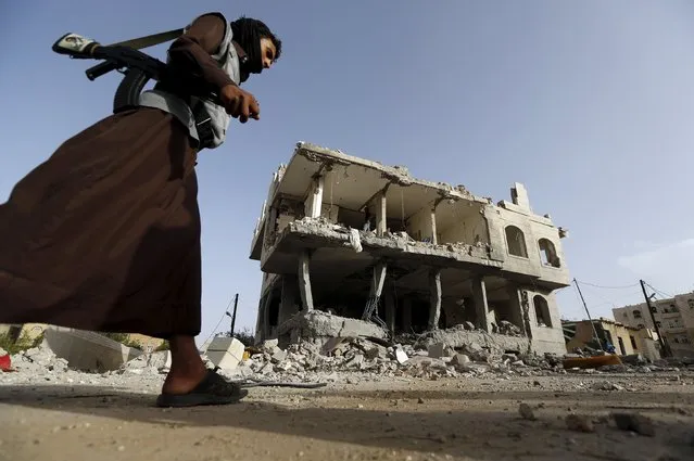 A Houthi militant walks past a house destroyed by an air strike in Sanaa April 26, 2015. (Photo by Khaled Abdullah/Reuters)