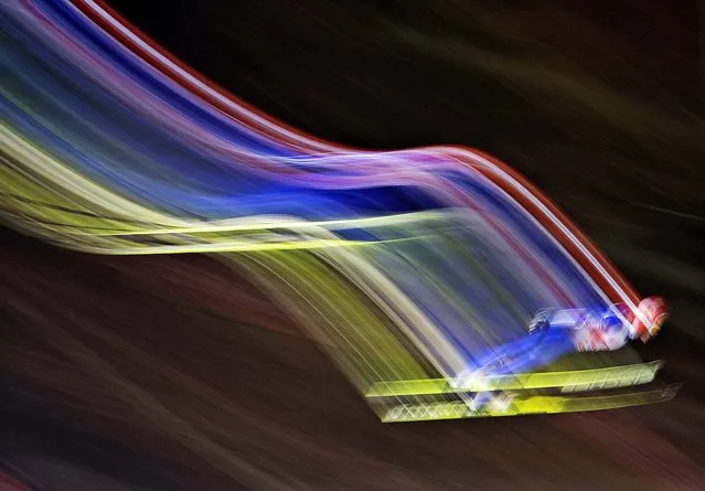 In this picture taken with a time exposure Richard Freitag of Germany soars through the air during the qualification at the FIS World Cup ski jumping in Willingen, Germany, Friday, January 31, 2014. (Photo by Jens Meyer/AP Photo)