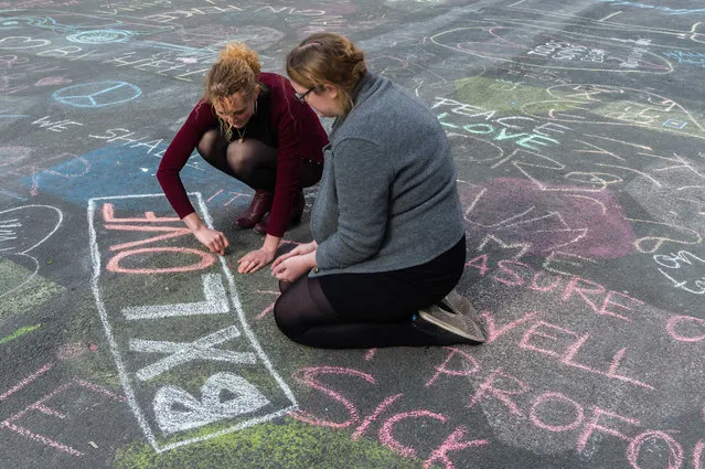 Two people write solidarity messages in chalk outside the stock exchange in Brussels on Tuesday, March 22, 2016. Explosions, at least one likely caused by a suicide bomber, rocked the Brussels airport and subway system Tuesday, prompting a lockdown of the Belgian capital and heightened security across Europe. At least 26 people were reported dead. (Photo by Geert Vanden Wijngaert/AP Photo)