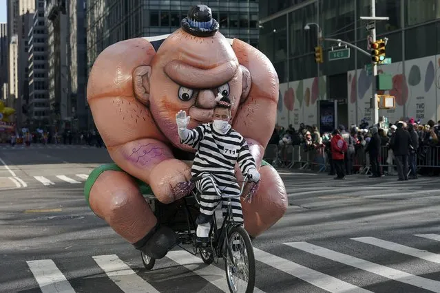 The Tough Guy balloon is driven down Sixth Avenue on a bicycle during the Macy's Thanksgiving Day Parade, Thursday, November 25, 2021, in New York. The Macy's Thanksgiving Day Parade is returning in full, after being crimped by the coronavirus pandemic last year.   (Photo by Jeenah Moon/AP Photo)