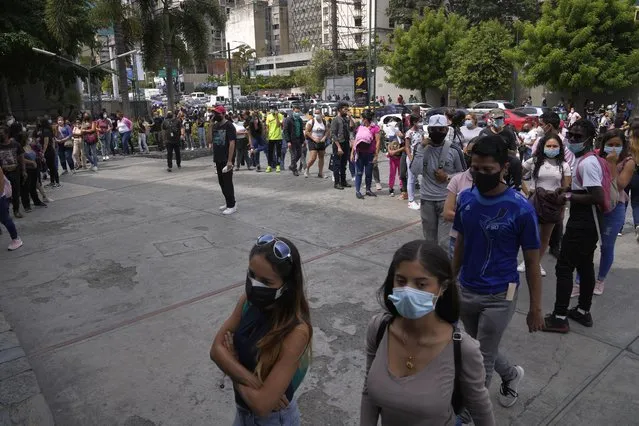 Shoppers, wearing protective face masks, line up to enter the Sambil Mall, in Caracas, Venezuela, Friday, November 26, 2021. At malls and few stores, Venezuelans are taking the opportunity to buy clothes and other articles with generous Black Friday discounts. (Photo by Ariana Cubillos/AP Photo)