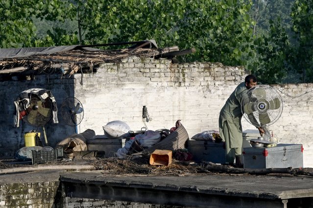 A resident gathers his belongings on the roof of his flood hit home as he prepares to leave following heavy rains in Charsadda district of Khyber Pakhtunkhwa province on April 17, 2024. At least 41 people have died in storm-related incidents across Pakistan since April 12, including 28 killed by lightning, officials said on April 15. (Photo by Abdul Majeed/AFP Photo)