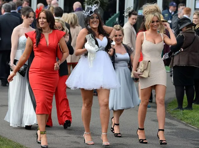 Racegoers arrive for “Ladies Day” at the Grand National horse race meeting at Aintree in Liverpool, northwest England, on April 4, 2014. The annual three day meeting culminates in the Grand National which is run over a distance of four miles and four furlongs (7,242 metres), and is the biggest betting race in the United Kingdom. (Photo by Ndrew Yates/AFP Photo)