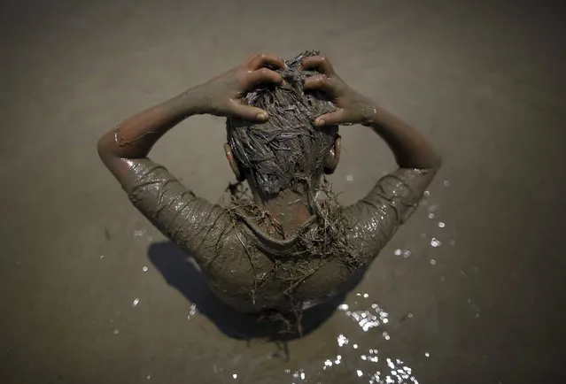 A boy scratches his head as he plays on the mud during the Asar Pandhra festival in Pokhara valley, west of Nepal's capital Kathmandu, June 30, 2015. (Photo by Navesh Chitrakar/Reuters)