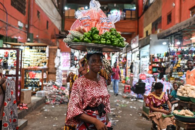 A street vendor carries vegetables on her head at the Adjame main market in Abidjan, Ivory Coast on March 7, 2024. (Photo by Issouf Sanogo/AFP Photo)