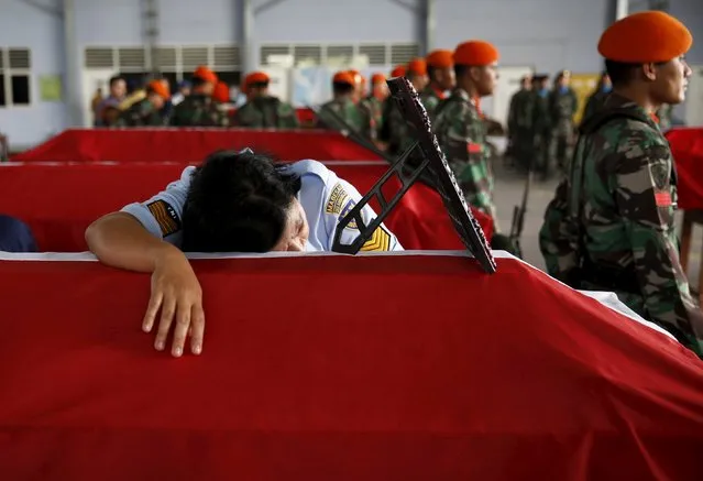 Swet Eka, an Indonesian soldier, mourns on the coffin of her husband (also a soldier), one of the victims in an Indonesian military C-130 Hercules transport plane that crashed into a residential area, inside military airbase in Medan, Indonesia North Sumatra province July 1, 2015. (Photo by Reuters/Beawiharta)