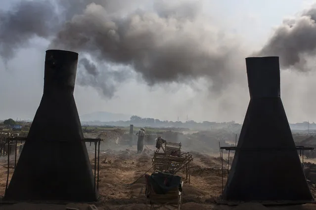 A worker adjusts an oven door of a kiln at a brick making factory in Mandalay, Myanmar, Friday December 11, 2015. For centuries brick-making has existed in Myanmar, nowadays brick-makers earn roughly the country's national minimum wage of about 3600 Kyat (just under $3) per day for work. (Photo by Hkun Lat/AP Photo)