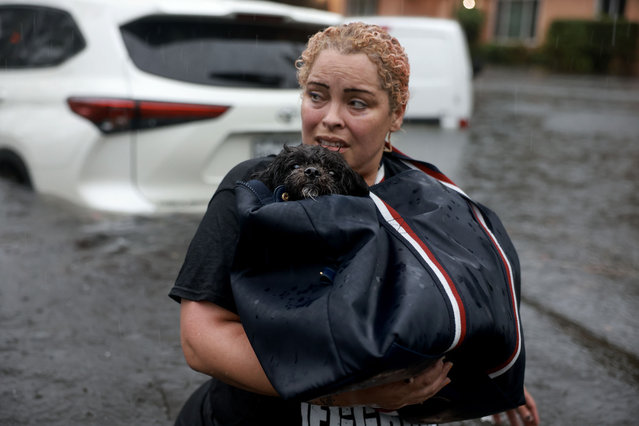 Iraida Rodriguez carries her dog, Benji, as she evacuates from her flooded home on June 12, 2024, in Hollywood, Florida. As tropical moisture passes through the area, areas have become flooded due to the heavy rain.  (Photo by Joe Raedle/Getty Images)