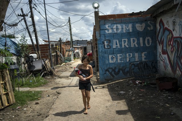 A girl carries a soft drink bottle through the Puerta 8 suburb north of Buenos Aires, Argentina, where police say contaminated cocaine may have been sold, Friday, February 4, 2022. A batch of cocaine has killed at least 23 people and hospitalized many more in Argentina, according to police. (Photo by Rodrigo Abd/AP Photo)