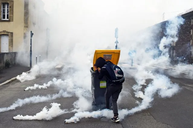 A demonstrator holds a wheelie bin to protect himself from tear gas canisters, during a demonstration against the government's planned labour law reforms, in Rennes, on May 17, 2016. The Socialist government last week survived a vote of no-confidence, which was called by the centre-right opposition, after it forced through the labour market reform bill without parliament's approval. (Photo by Damien Meyer/AFP Photo)