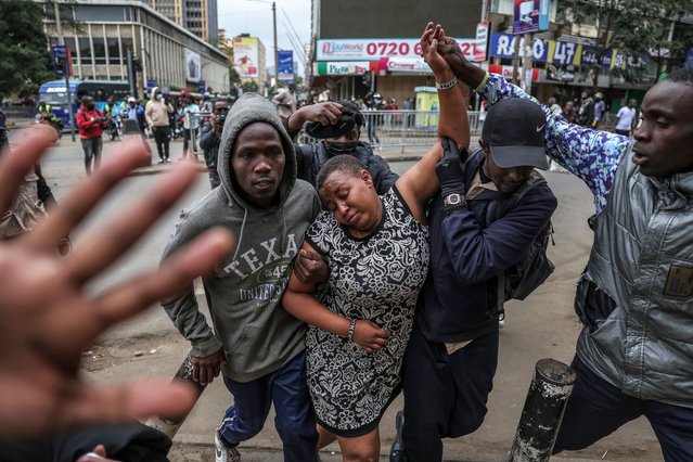 A woman (C) suffering from tear gas inhalation is helped away by during renewed demonstrations in Nairobi on July 16, 2024. Police were out in force in the centre of Kenya's capital on Tuesday after calls for more demonstrations against the embattled government of President William Ruto. Activists led by young Gen-Z Kenyans launched peaceful rallies a month ago against deeply unpopular tax hikes but they descended into deadly violence last month, prompting Ruto to drop the planned increases. (Photo by Tony Karumba/AFP Photo)