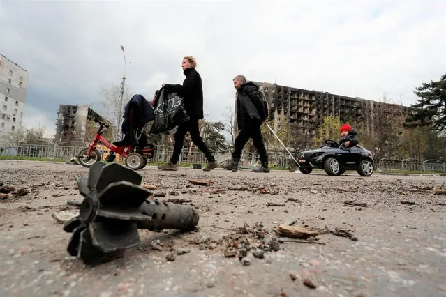 Family members are seen in a street near residential buildings damaged during Ukraine-Russia conflict in the southern port city of Mariupol, Ukraine on April 22, 2022. (Photo by Alexander Ermochenko/Reuters)