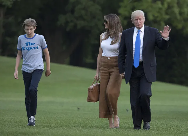 President Donald Trump waves as he walks with first lady Melania Trump and their son, Barron Trump, from Marine One across the South Lawn to the White House in Washington, Sunday, June 11, 2017, as they returned from Bedminster, N.J. (Photo by Carolyn Kaster/AP Photo)