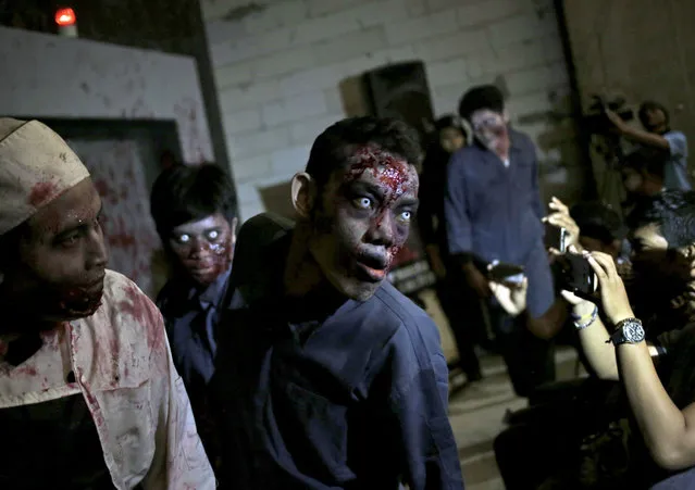 Reporters use their mobile phones to take pictures of actors dressed as zombies during the opening of “Dead Prison”, a zombie-themed performance space at a shopping mall in Jakarta, Indonesia, Friday, June 10, 2016. The attraction, which is run by Indonesia's Zombie Lovers Community was inspired by U.S. television series “The Walking Dead”. (Photo by Dita Alangkara/AP Photo)