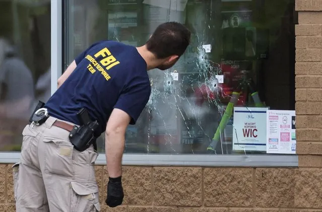 A member of the FBI looks at bullet holes through the glass at the scene of a shooting at a Tops supermarket in Buffalo, New York, U.S. May 16, 2022. (Photo by Brendan McDermid/Reuters)