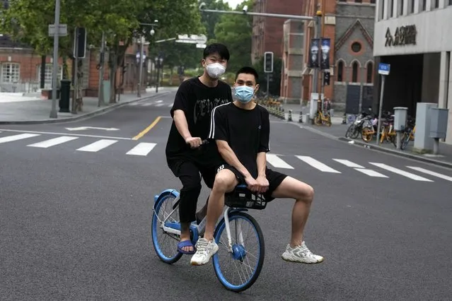 Residents share a bike as they ride on an empty street, Wednesday, June 1, 2022, in Shanghai. (Photo by Ng Han Guan/AP Photo)