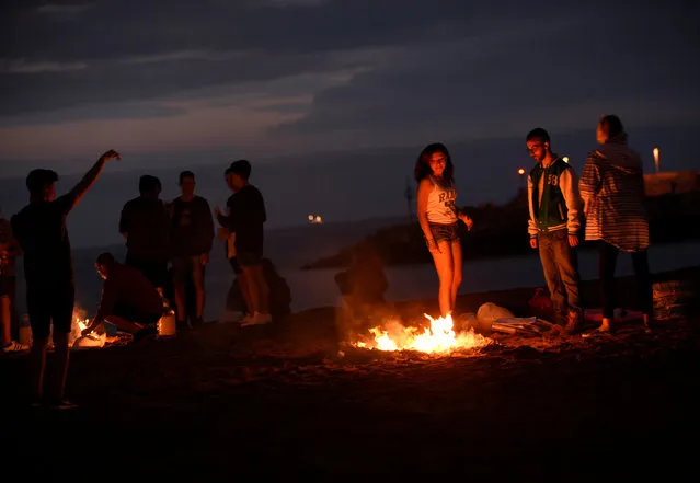 People looking at a bonfire during the traditional San Juan's (Saint John) night in Gijon, northern Spain, June 23, 2016. (Photo by Eloy Alonso/Reuters)