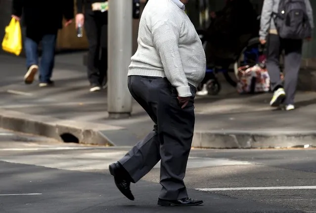 A man crosses a main road as pedestrians carrying food walk along the footpath in central Sydney, Australia, August 12, 2015. Fast food may be falling out of favour in many countries around the world but companies are making healthy profits and boldly innovating in the unlikely market of Australia. (Photo by David Gray/Reuters)