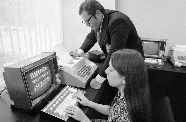 High-speed movement of securities orders on the Midwest Stock Exchange is handled by this new computerized communications device in the Chicago officer of the Exchange  June 16, 1971. While R. Thomas Rehwald, senior Vice-President and treasurer of the Midwest Stock Exchange Serviced Corp., watches, Arois Ruehl types information into the machine for storage and transmission. The system, Signet 80, handles paperwork more than 20 times faster than any previous system. (Photo by Charles Knoblock/AP Photo)