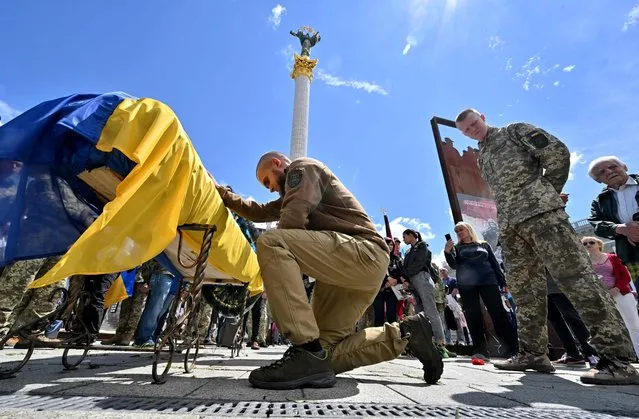 Ukrainian servicemen mourn on the coffin of their comrade Oleh Kutsyn, commander of the “Karpatska Sitch” battalion killed during the war against Russia, during a funeral ceremony at Kyiv's “Maidan” Independence Square on June 22, 2022. (Photo by Sergei Supinsky/AFP Photo)