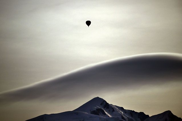 This photograph taken from Cordon ski resort near Megeve on February 18, 2024 near Cordon ski resort near Megeve, shows a hot air balloon drifing over the Massif du Mont-Blanc mountains range in the French Alps in France. (Photo by Olivier Chassignole/AFP Photo)