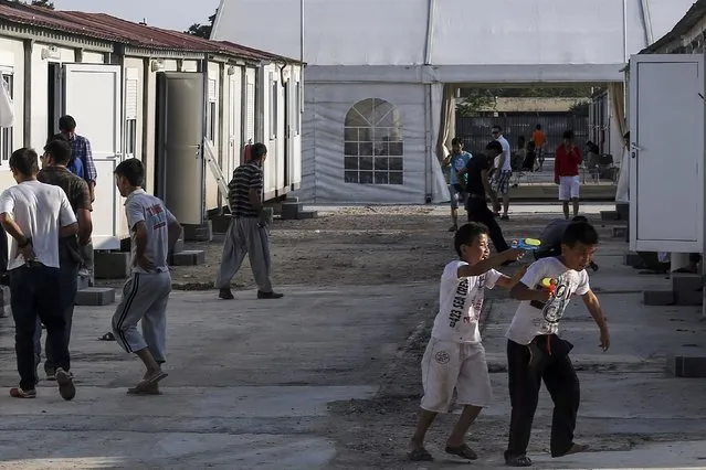 Two migrant boys (R) play at a newly-built reception center after being transferred from a park in Athens, Greece, August 16, 2015. (Photo by John Liakos/Reuters/Intimenews)