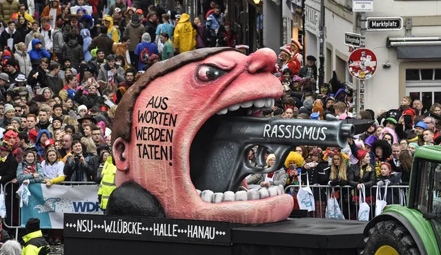 A carnival float depicts a racist with a gun in his mouth , reading “from words to action” during the traditional carnival parade in Duesseldorf, Germany, on Monday, February 24, 2020. The float reminds the NSU, the assaults in Hanau, Halle and on Walter Luebke. The foolish street spectacles in the carnival centers of Duesseldorf, Mainz and Cologne, watched by hundreds of thousands of people, are the highlights in Germany's carnival season on Rosemonday. (Photo by Martin Meissner/AP Photo)