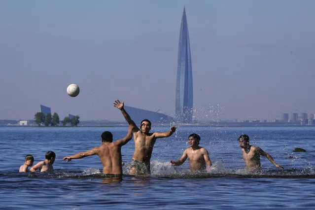 People play volleyball in the Gulf of Finland in St. Petersburg, Russia, Saturday, June 25, 2022, with the business tower Lakhta Centre, the headquarters of Russian gas monopoly Gazprom in the background. (Photo by Dmitri Lovetsky/AP Photo)