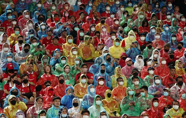Fans wearing rain ponchos and face masks watch the Manchester United v Liverpool preseason friendly match, at Rajamangala National Stadium, Bangkok, Thailand on July 12, 2022. (Photo by Chalinee Thirasupa/Reuters)