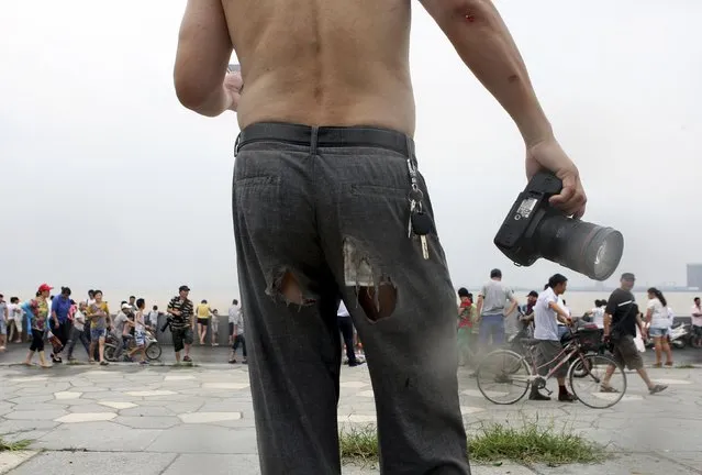 A man's trousers is torn as he fell to the ground after being hit by waves caused by a tidal bore, which surged past a barrier on the banks of Qiantang River, in Hangzhou, Zhejiang province August 13, 2014. (Photo by Reuters/Stringer)