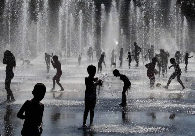 Children play in a fountain during a hot and sunny summer day in Nice, southeastern France, July 31, 2014. (Photo by Eric Gaillard/Reuters)
