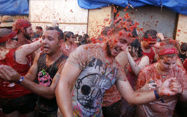 People throw tomatoes at each other, during the annual “Tomatina” tomato fight fiesta in the village of Bunol, 50 kilometers outside Valencia, Spain, Wednesday, August 27, 2014. (Photo by Alberto Saiz/AP Photo)