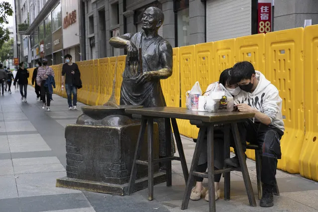 In this Wednesday, April 8, 2020, photo, a couple share a quiet moment on the streets of Wuhan in central China's Hubei province. (Photo by Ng Han Guan/AP Photo)