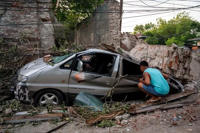 A man inspects a damaged car in the aftermath of an earthquake in Vigan City, Ilocos Sur, Philippines, July 28, 2022. (Photo by Lisa Marie David/Reuters)