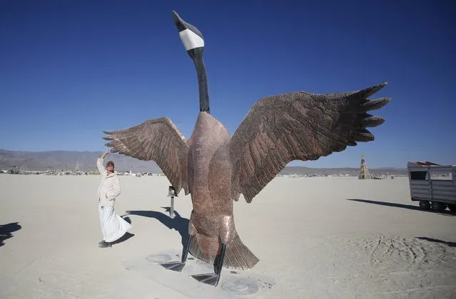 Participant Lea touches the art installation “Penny the Goose” during the Burning Man “Carnival of Mirrors” arts and music festival in the Black Rock Desert of Nevada, September 4, 2015. Approximately 70,000 people from all over the world are gathering at the sold-out festival to spend a week in the remote desert to experience art, music and the unique community that develops. (Photo by Jim Urquhart/Reuters)
