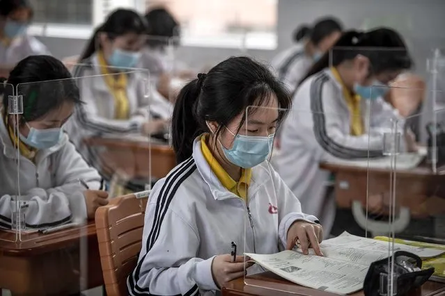 High school senior students study with plastic partitions in a classroom in Wuhan in China's central Hubei province on May 6, 2020. Senior school students in 121 institutions were back in front of chalk boards and digital displays for the first time on May 6 since their city – the ground zero of the coronavirus pandemic – shut down in January. (Photo by AFP Photo/China Stringer Network)
